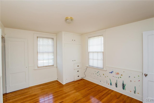 unfurnished bedroom featuring multiple windows, a closet, and light hardwood / wood-style flooring