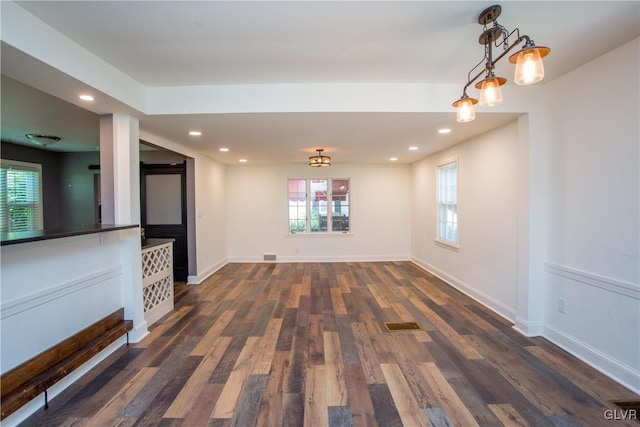 unfurnished living room featuring dark wood-type flooring and a wealth of natural light