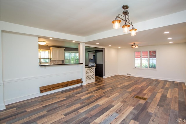 unfurnished living room with a barn door and dark hardwood / wood-style flooring