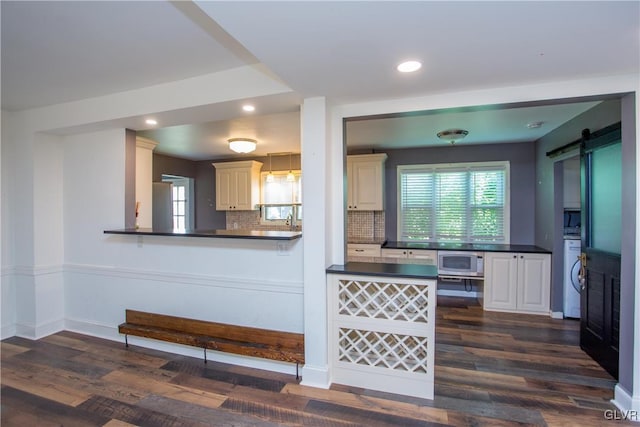 kitchen with stainless steel microwave, backsplash, a barn door, and kitchen peninsula