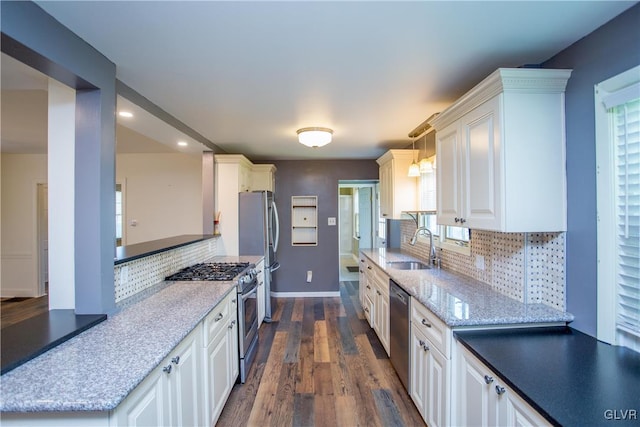 kitchen featuring appliances with stainless steel finishes, tasteful backsplash, sink, white cabinets, and hanging light fixtures