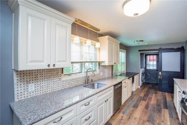 kitchen with appliances with stainless steel finishes, pendant lighting, white cabinetry, sink, and a barn door