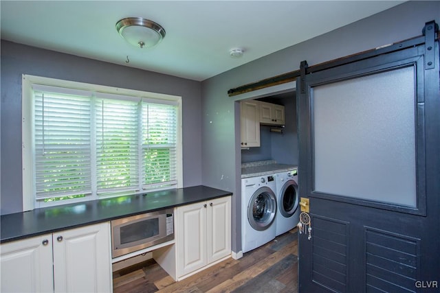 washroom featuring dark hardwood / wood-style floors, cabinets, a barn door, and washing machine and clothes dryer