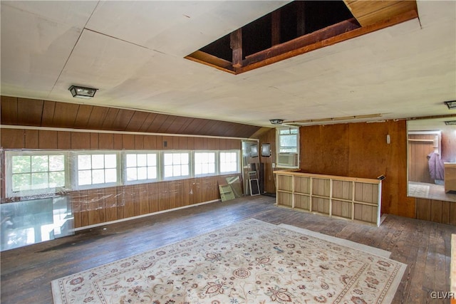 unfurnished living room with dark wood-type flooring, wooden walls, and vaulted ceiling