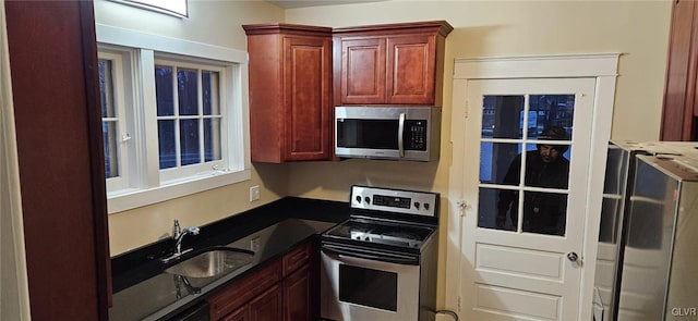 kitchen featuring dark stone countertops, sink, and stainless steel appliances