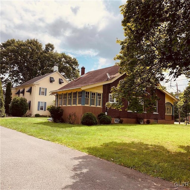 view of front of home with a sunroom and a front yard