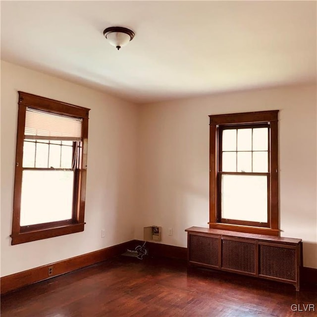 empty room with dark hardwood / wood-style flooring and radiator