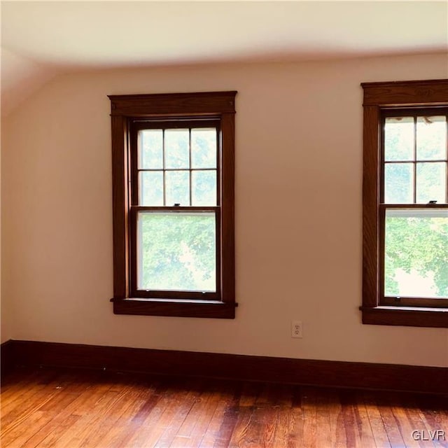 spare room with hardwood / wood-style floors, vaulted ceiling, and a wealth of natural light