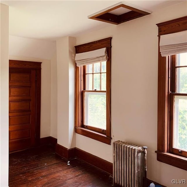 spare room with dark wood-type flooring and radiator heating unit