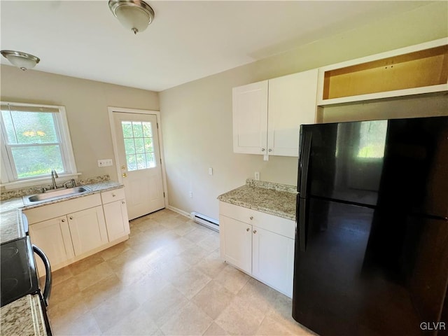 kitchen featuring sink, white cabinetry, a baseboard heating unit, light stone countertops, and black fridge