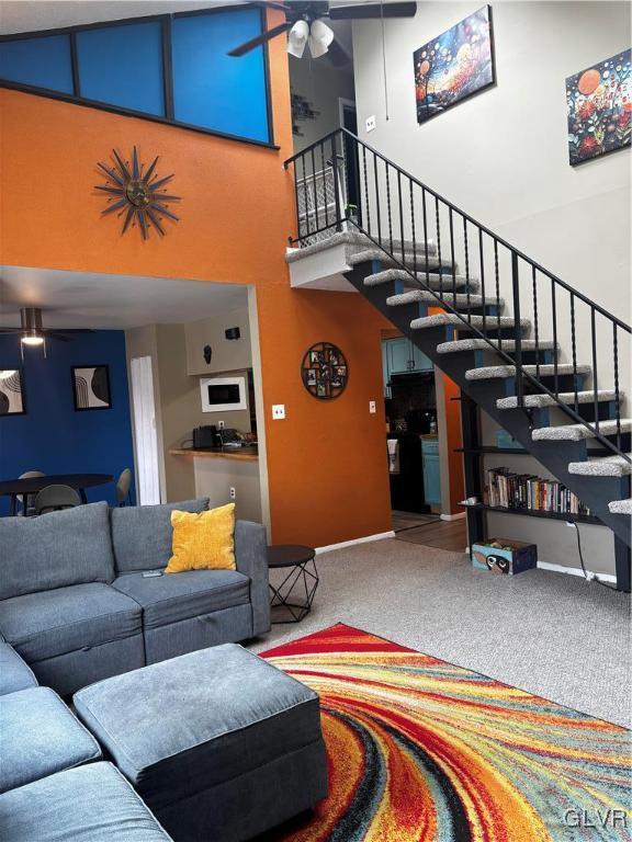 carpeted living room with a towering ceiling and ceiling fan