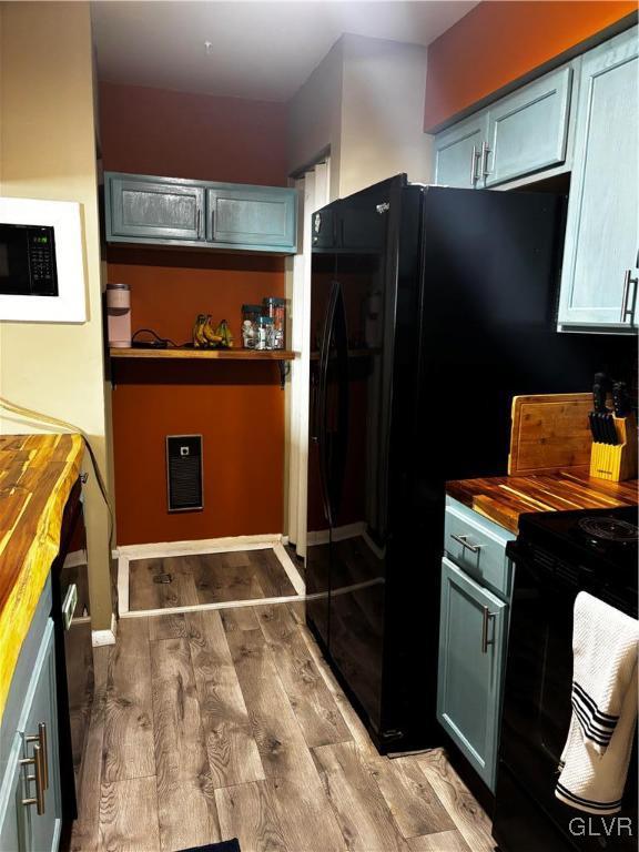 kitchen with wooden counters, light hardwood / wood-style floors, and black appliances