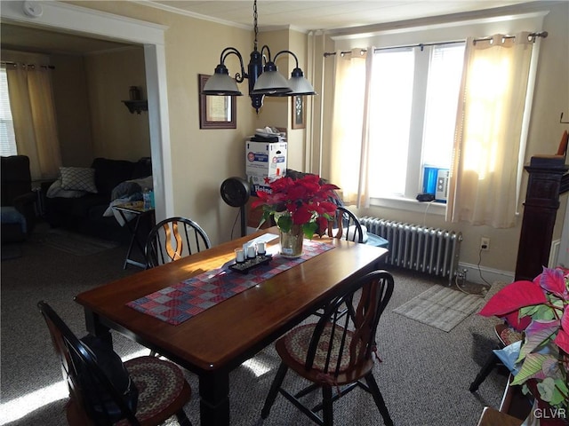 dining room featuring ornamental molding, carpet flooring, radiator heating unit, and an inviting chandelier