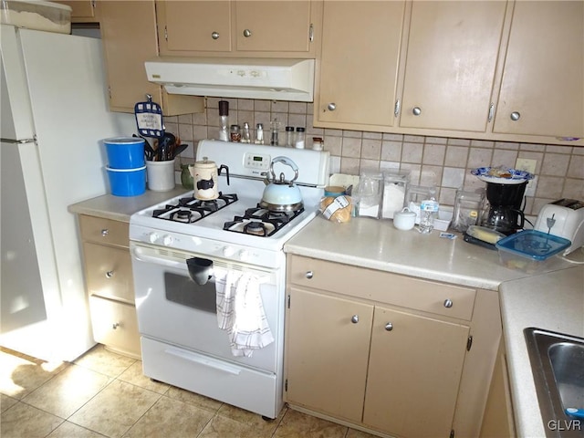 kitchen with sink, light tile patterned floors, backsplash, and white appliances