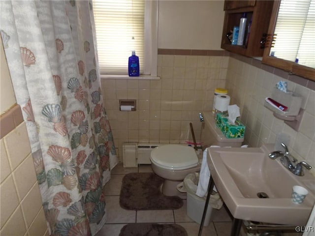 bathroom with baseboard heating, tile patterned flooring, sink, and tile walls