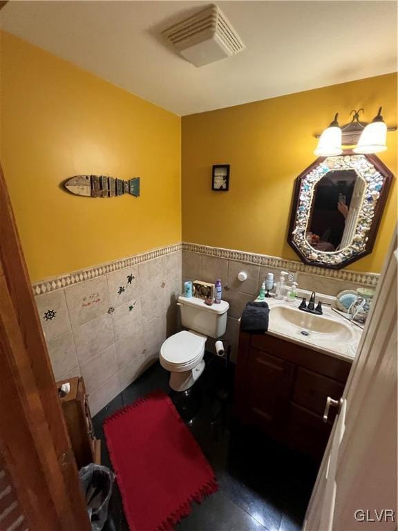 bathroom featuring vanity, toilet, and tile walls