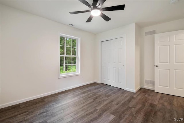 unfurnished bedroom with dark wood-type flooring, a closet, and ceiling fan