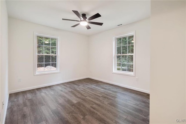 spare room with dark hardwood / wood-style flooring, ceiling fan, and a healthy amount of sunlight