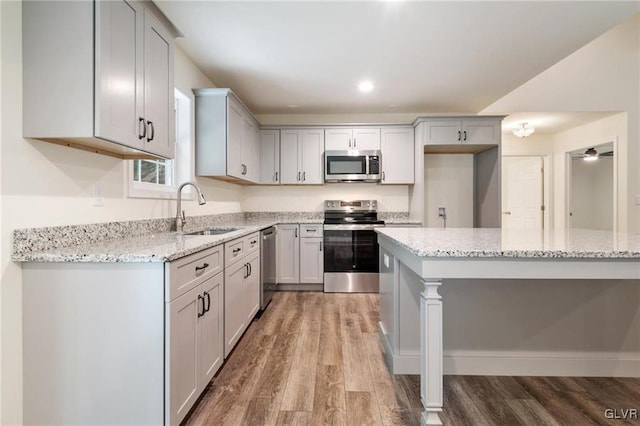 kitchen featuring light stone counters, sink, stainless steel appliances, and light wood-type flooring