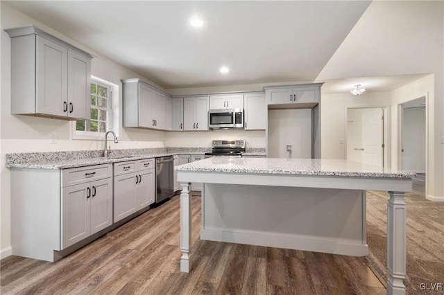 kitchen featuring light stone counters, hardwood / wood-style flooring, stainless steel appliances, and a kitchen island