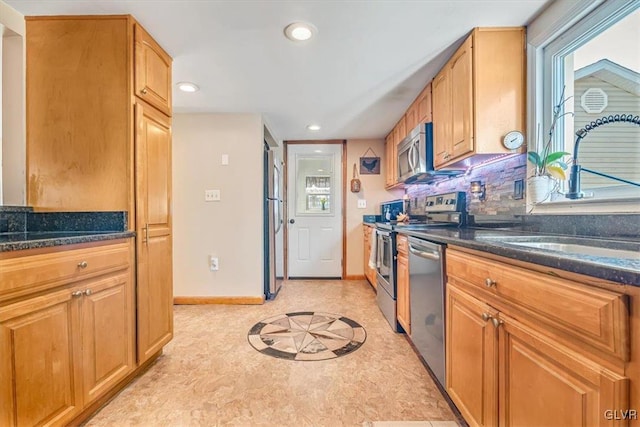 kitchen featuring dark stone countertops, sink, tasteful backsplash, and appliances with stainless steel finishes