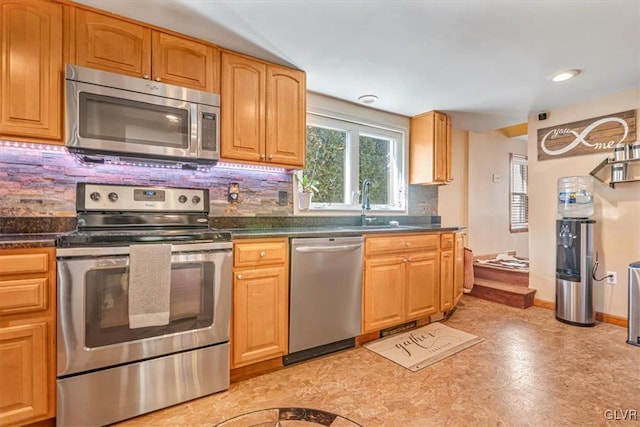 kitchen with appliances with stainless steel finishes, sink, and decorative backsplash