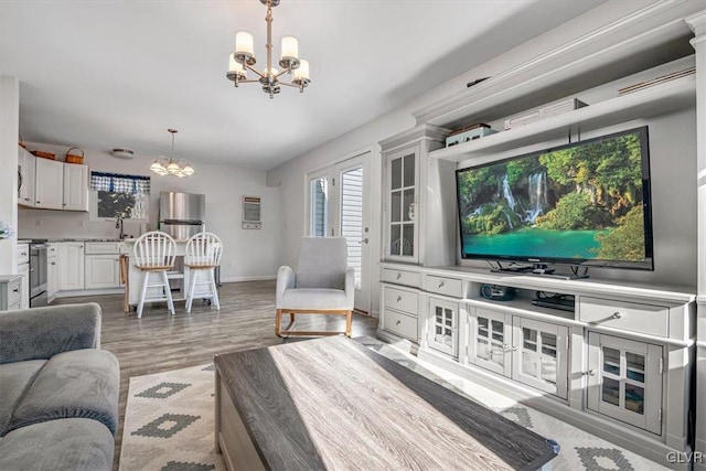 living room featuring a chandelier, sink, and light hardwood / wood-style flooring