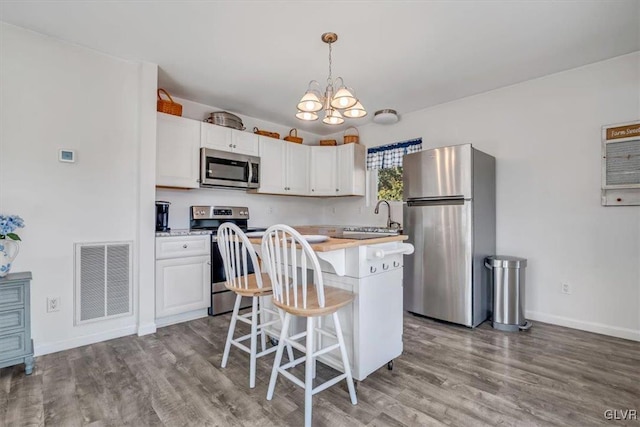 kitchen with pendant lighting, appliances with stainless steel finishes, a center island, and white cabinets