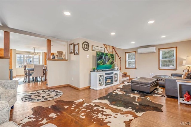 living room with a wall mounted air conditioner and light hardwood / wood-style floors