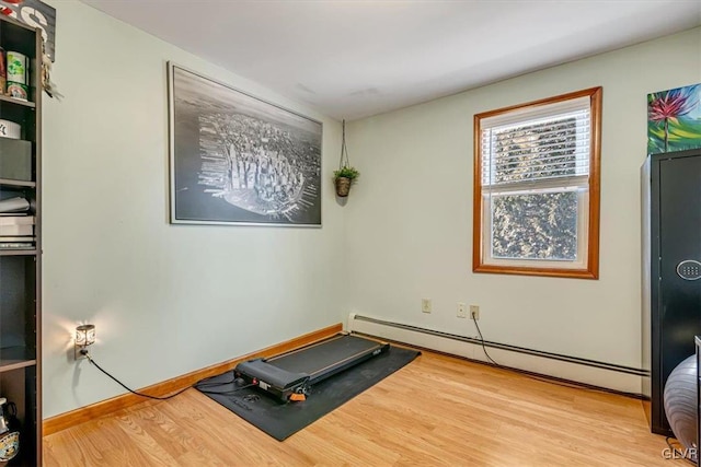 workout area featuring wood-type flooring and a baseboard heating unit