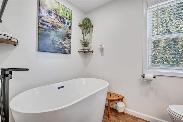 bathroom featuring hardwood / wood-style flooring, a bath, and toilet