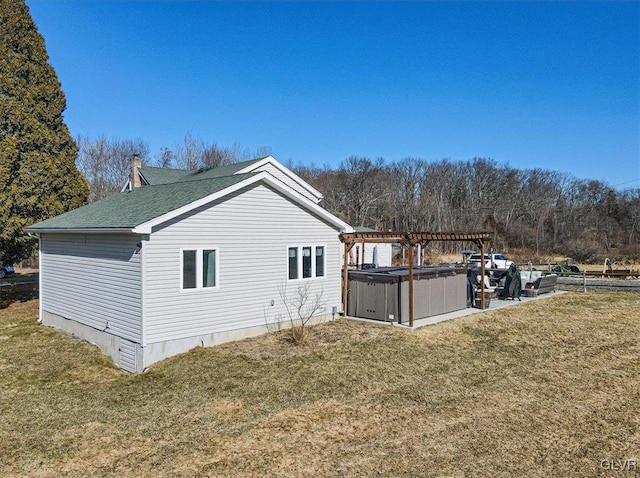 view of side of property with a hot tub, a yard, and a pergola