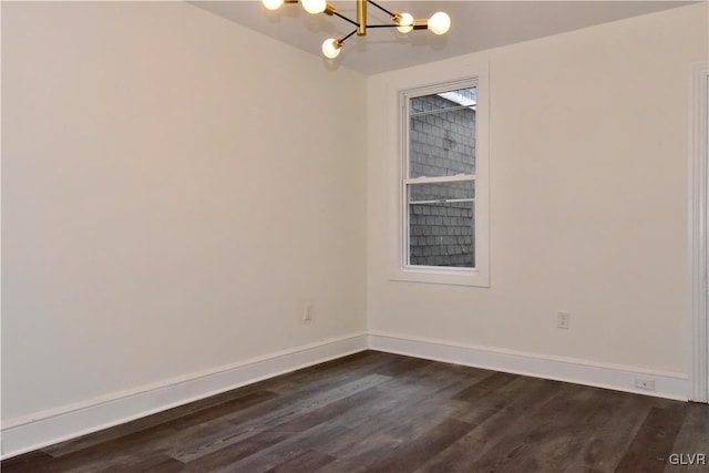 spare room with dark wood-type flooring and a notable chandelier