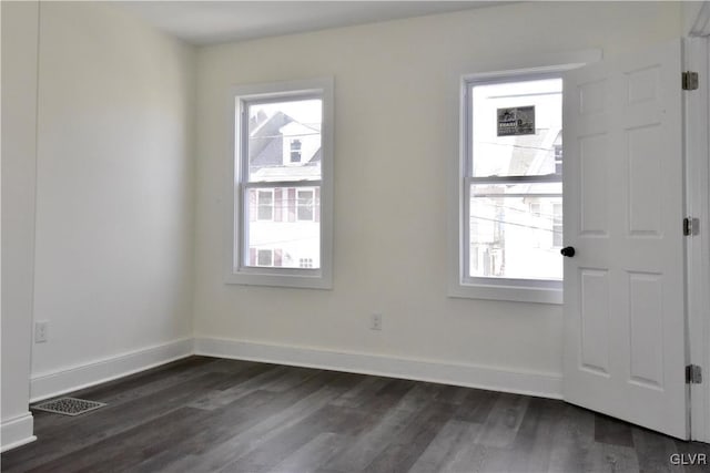 empty room with a healthy amount of sunlight and dark hardwood / wood-style flooring