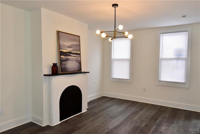 unfurnished living room with a notable chandelier, dark wood-type flooring, and plenty of natural light