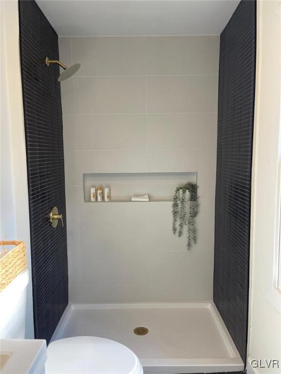 bathroom featuring tiled shower, vanity, and toilet