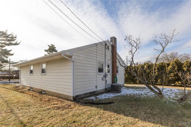 view of side of property featuring a yard and central AC