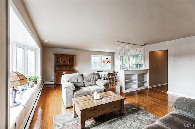 living room with a baseboard heating unit and wood-type flooring