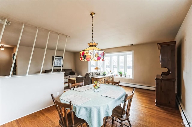 dining space with hardwood / wood-style floors and a baseboard heating unit