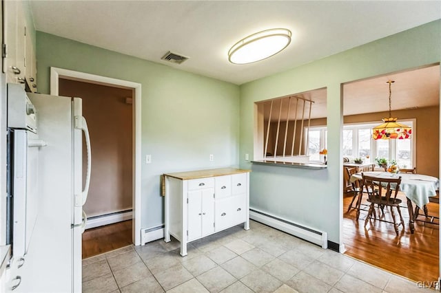 kitchen with baseboard heating, white refrigerator, and white cabinets