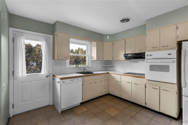 kitchen featuring cream cabinets, sink, white appliances, and decorative backsplash