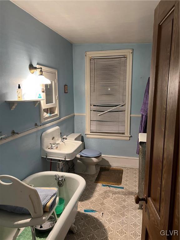 bathroom with tile patterned flooring, a bathing tub, sink, and toilet