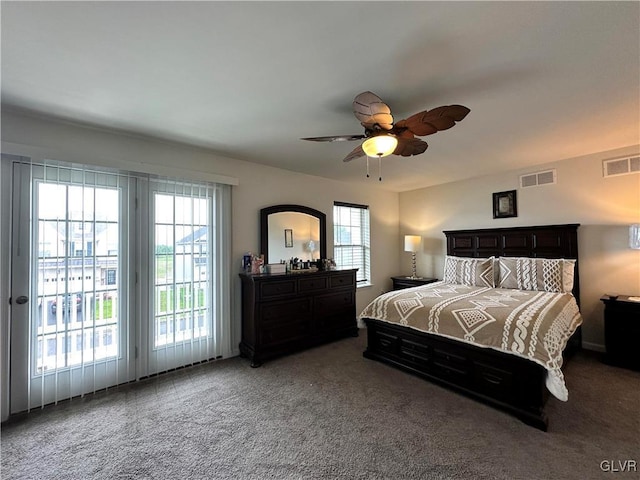 bedroom with multiple windows, dark carpet, and ceiling fan