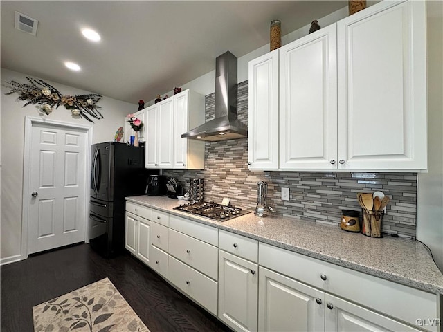 kitchen with wall chimney range hood, dark hardwood / wood-style floors, tasteful backsplash, stainless steel gas cooktop, and white cabinets