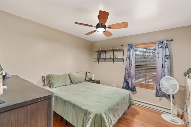 bedroom with a baseboard heating unit, wood-type flooring, and ceiling fan