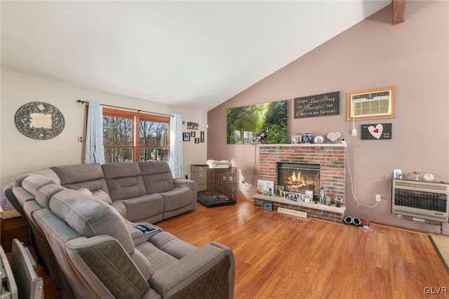 living room with heating unit, wood-type flooring, a wall mounted AC, vaulted ceiling, and a fireplace