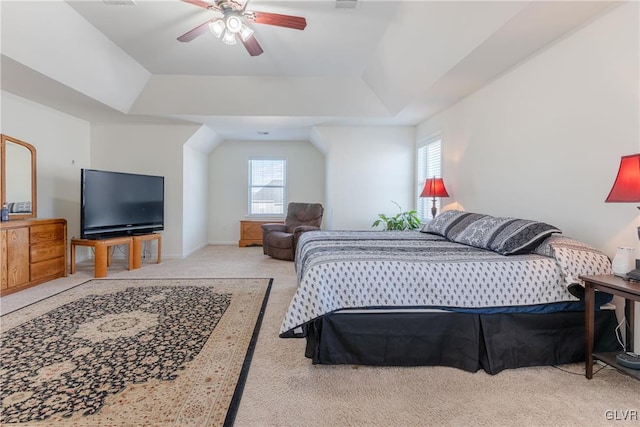 bedroom featuring a raised ceiling, light colored carpet, and ceiling fan