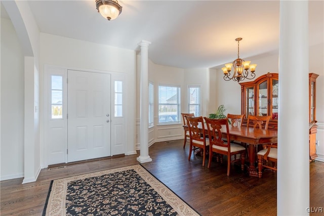 entrance foyer with an inviting chandelier, decorative columns, and dark hardwood / wood-style floors