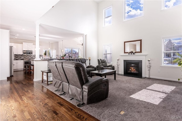 living room featuring dark hardwood / wood-style flooring, a wealth of natural light, and decorative columns