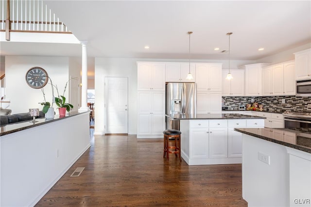 kitchen featuring appliances with stainless steel finishes, pendant lighting, decorative columns, white cabinetry, and dark hardwood / wood-style flooring